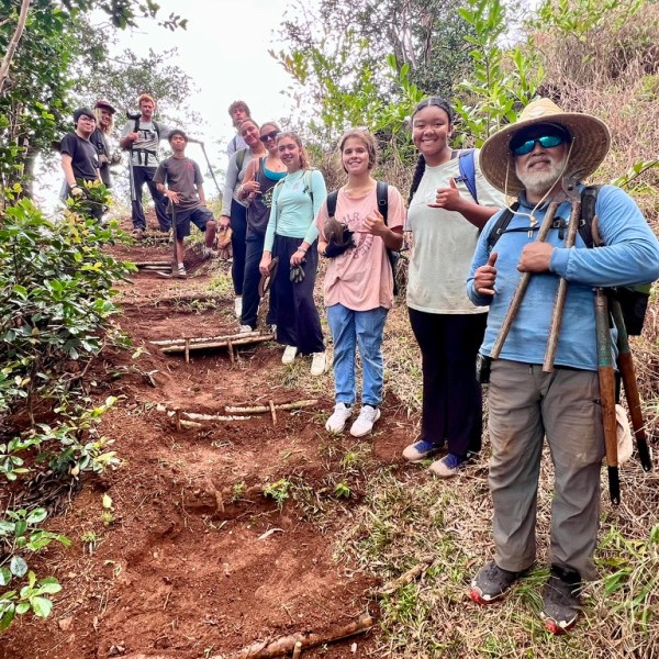 Group of hikers posing on a forest trail with tools.