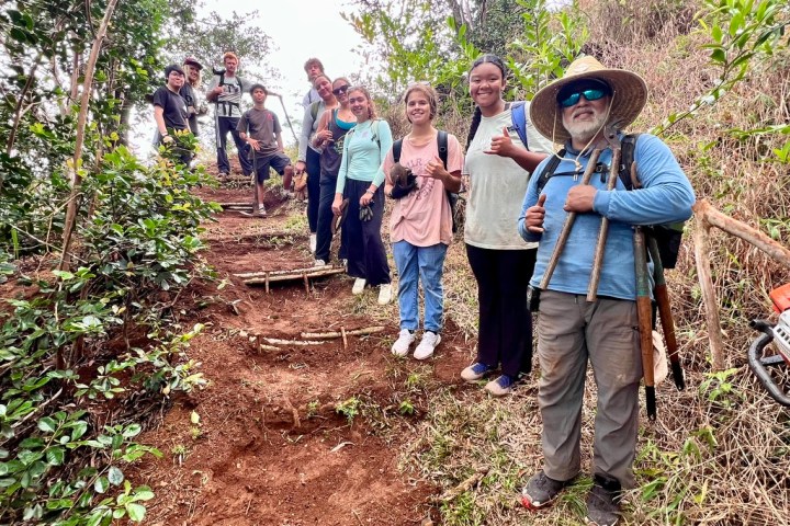 Group of hikers posing on a forest trail with tools.