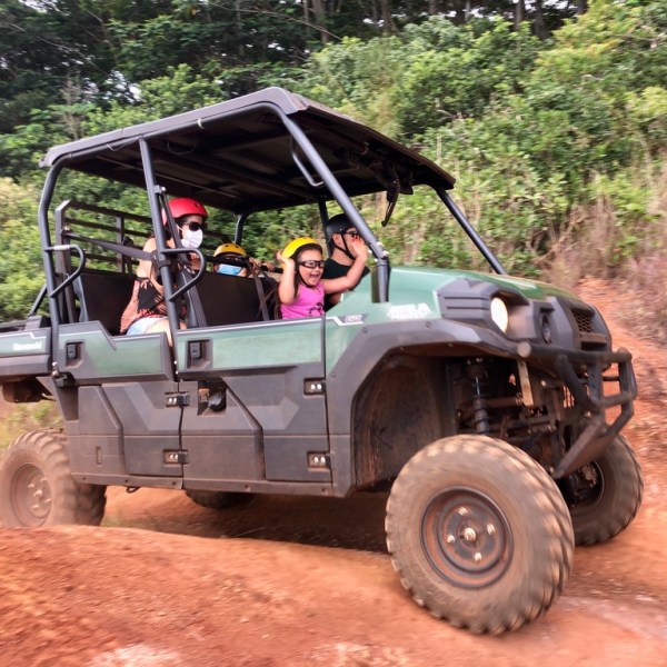 People riding in an off-road vehicle on a dirt path.