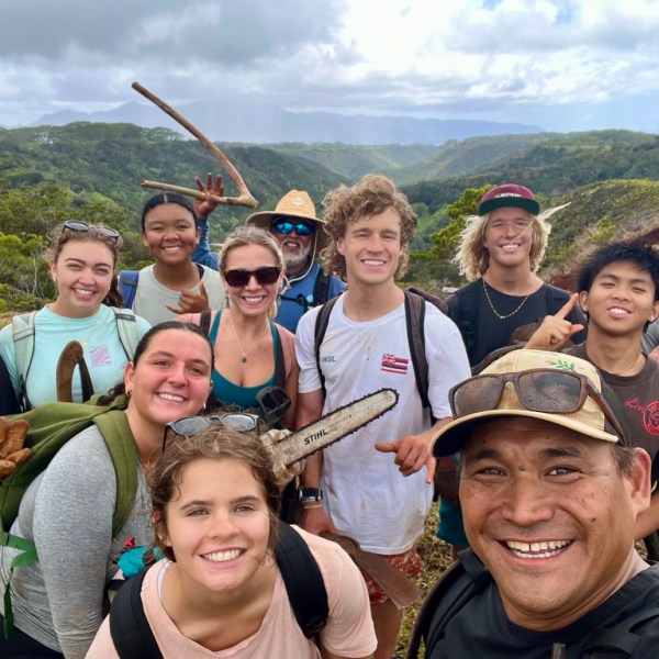 Group of people smiling outdoors in a hilly, green landscape.