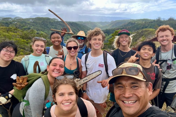 Group of people smiling outdoors in a hilly, green landscape.