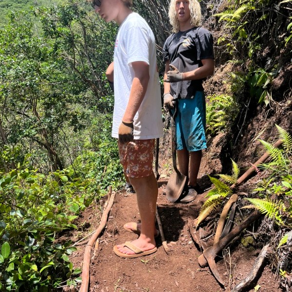 Two people standing on a forest trail with shovels.