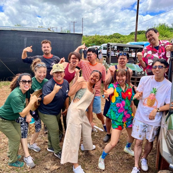 Group of people smiling and posing outdoors near off-road vehicles.