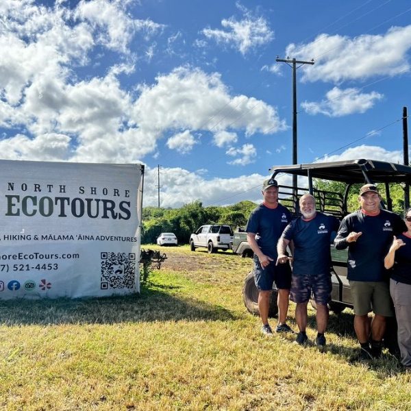 Group posing by North Shore Ecotours banner and off-road vehicle.